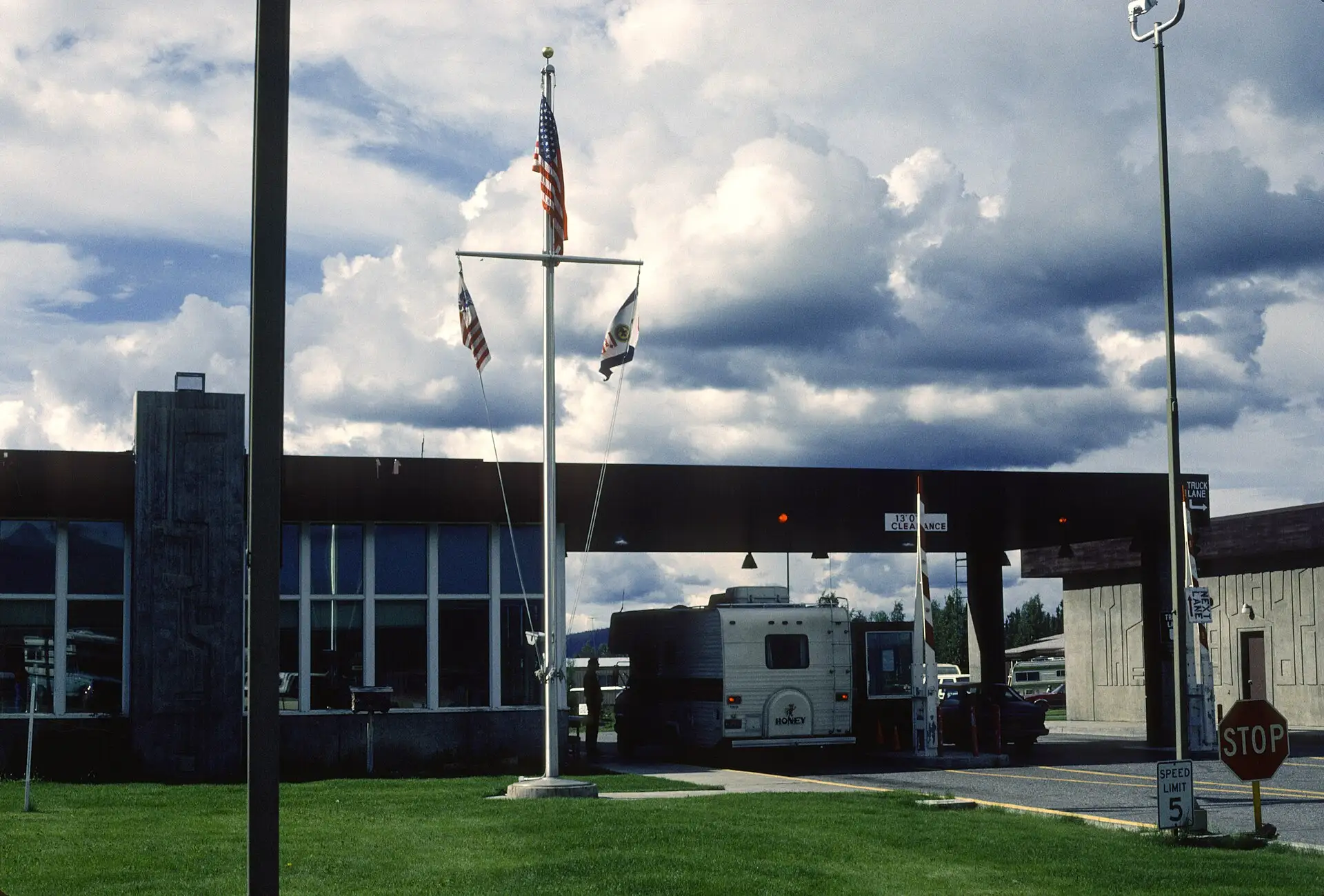 Welcome to Alaska sign and Alcan border port of entry buildings under a cloudy sky