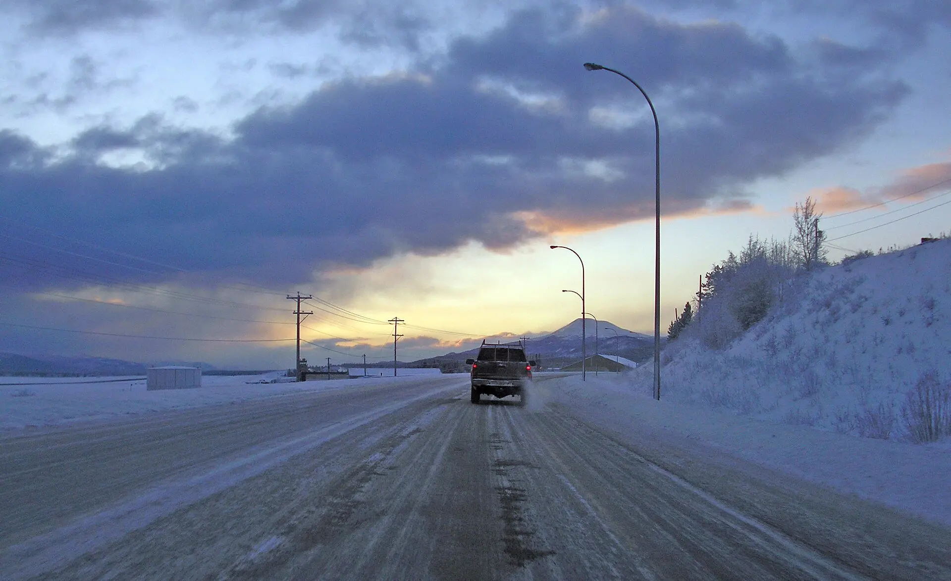 The Alaska Highway running past commercial buildings on the edge of Whitehorse