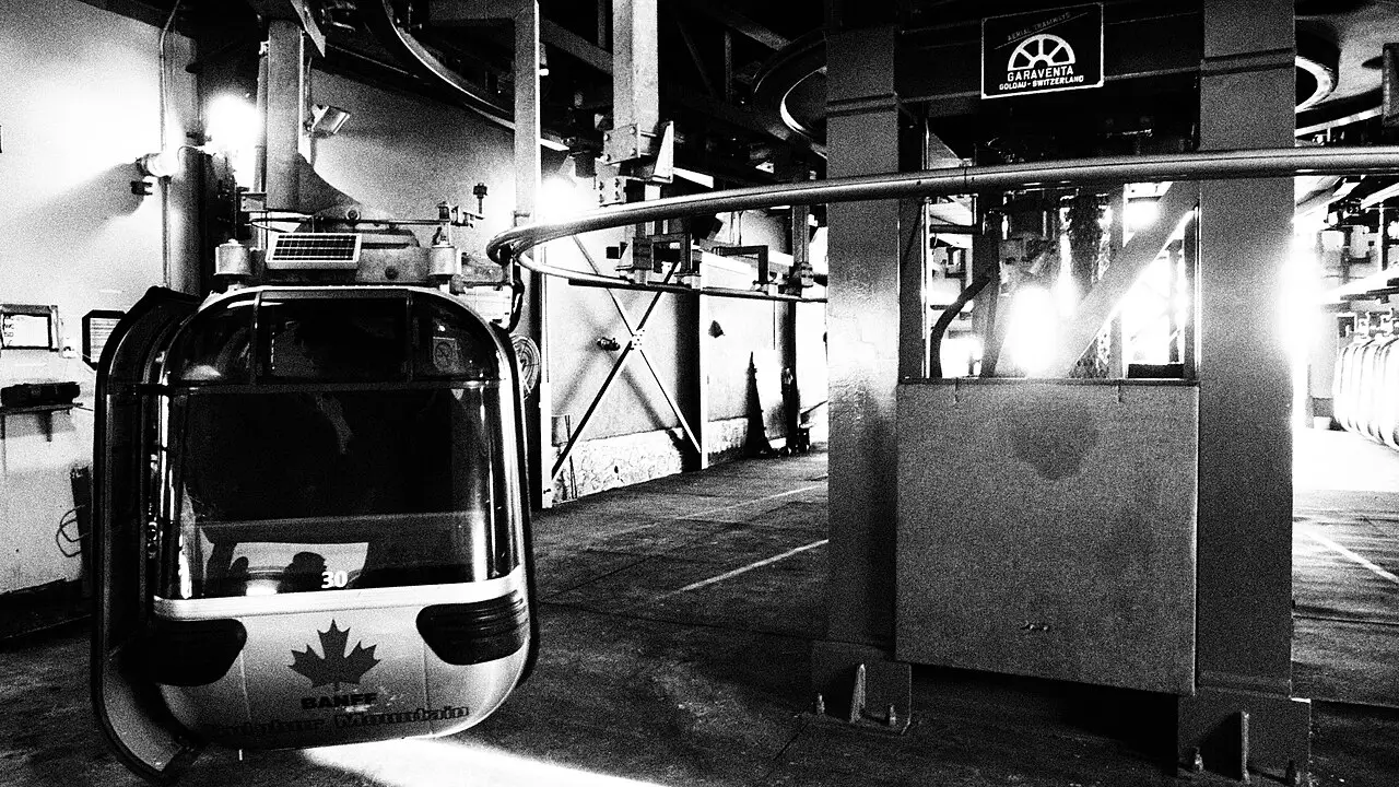 A Banff Gondola cabin suspended on cables above the forested slope of Sulphur Mountain