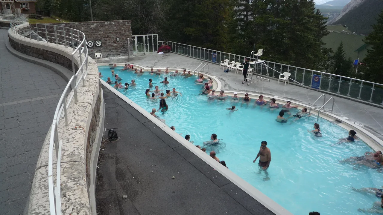 Bathers in the outdoor thermal pool at Banff Upper Hot Springs with the mountains behind
