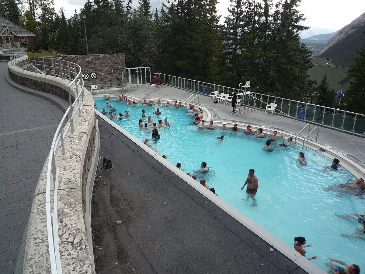 The outdoor pool at Banff Upper Hot Springs with steam and mountain forest around the deck