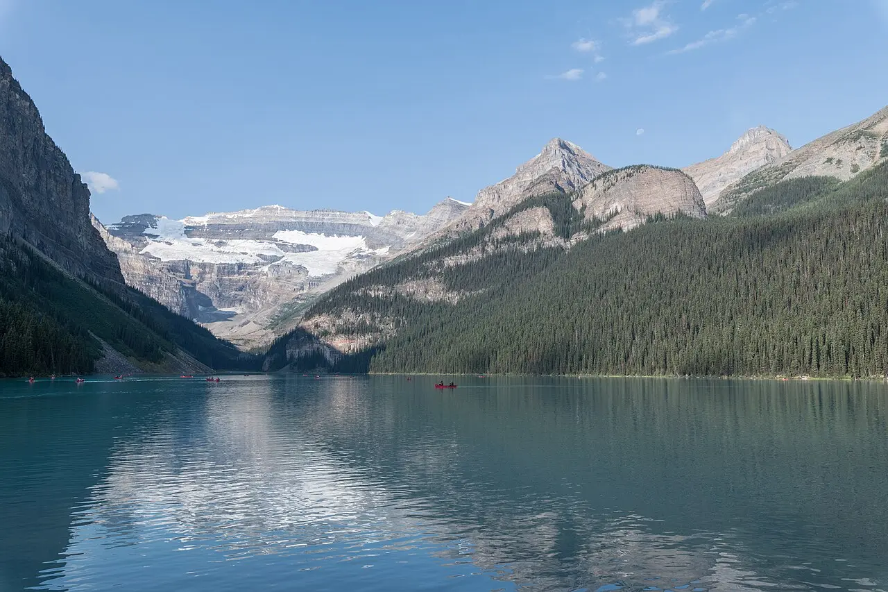 Canoes on the green water of Lake Louise with the Victoria Glacier and snowfields at the far end of the valley