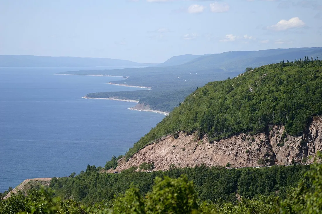 A high view over forested green highlands dropping to the blue sea from Cape Smokey
