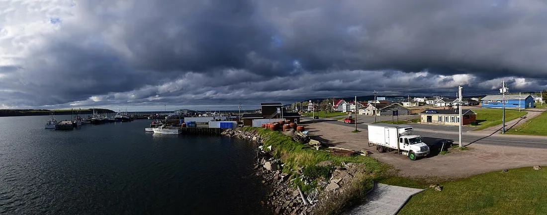 Fishing boats and wharves in Chéticamp harbour under dramatic dark storm clouds