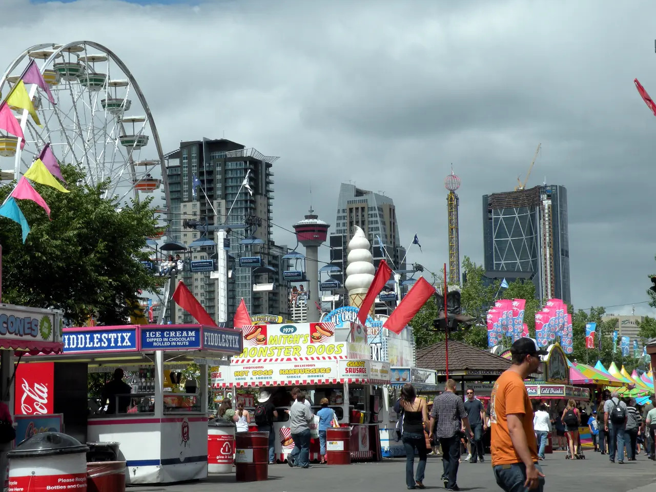 Ferris wheel and carnival rides of the Stampede midway against a cloudy sky