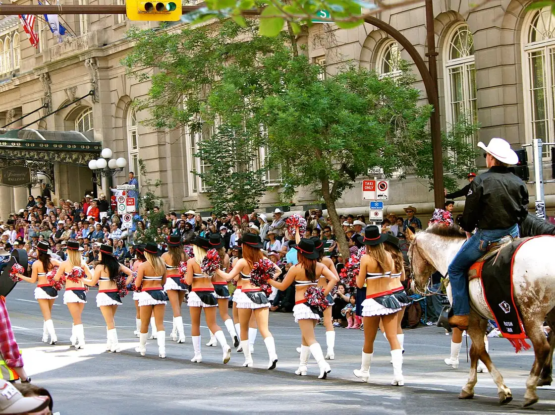 Mounted riders in western dress moving through downtown streets during the Calgary Stampede Parade
