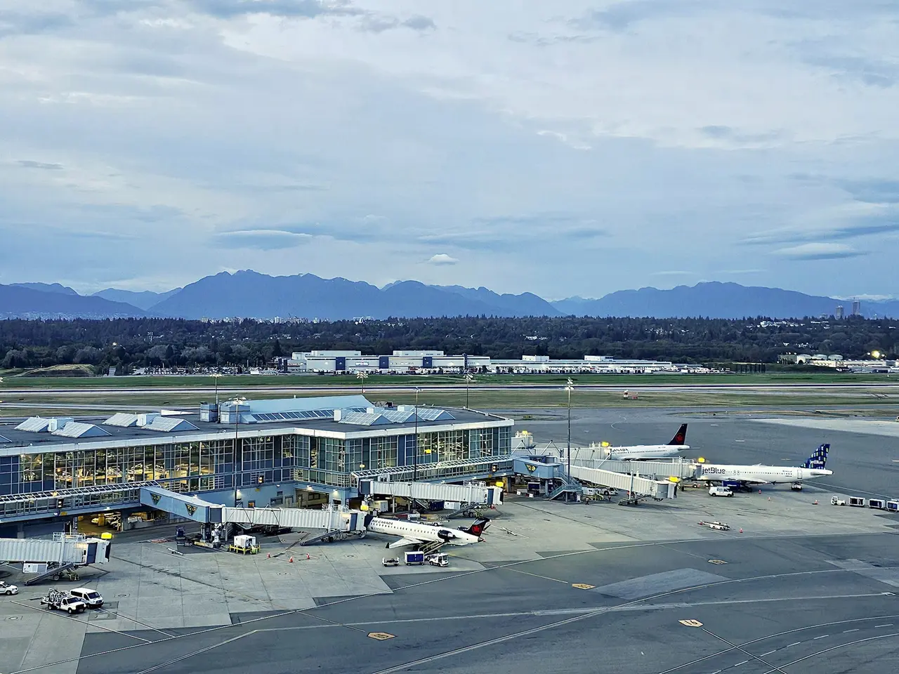 Vancouver International Airport seen from above, aircraft at the gates and the North Shore mountains behind