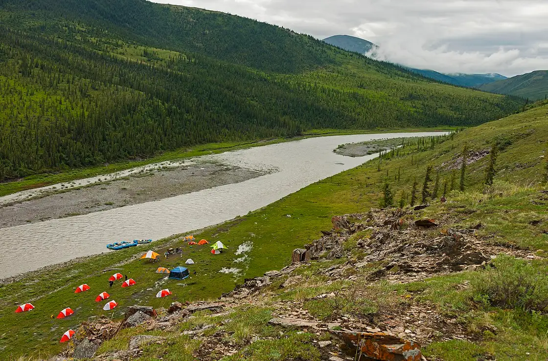 Small tents pitched on a gravel bar beside the braided Firth River in Ivvavik National Park