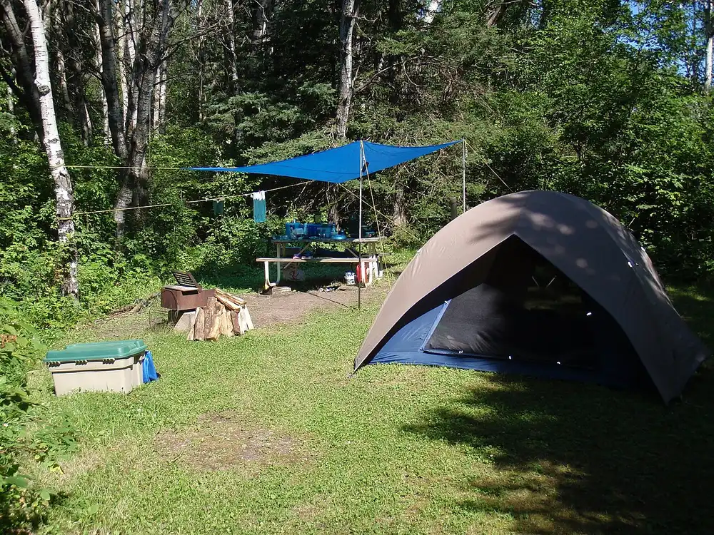A tent pitched beside a picnic table at a lakeside campsite in Riding Mountain National Park