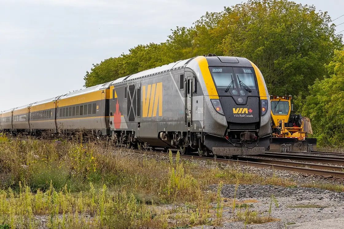 A modern VIA Rail Corridor train running through the Ontario countryside
