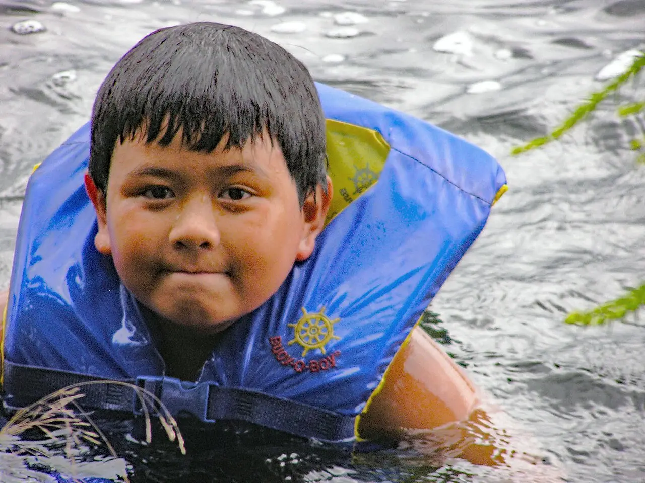 Person relaxing in a canoe on a calm lake with camping gear nearby