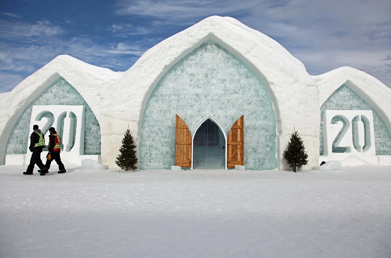 The snow and ice facade of the Hotel de Glace near Quebec City with arched entrances under a blue sky