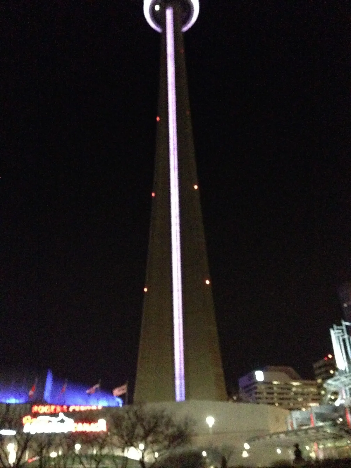 The floodlit base of the CN Tower in Toronto rising into the night sky