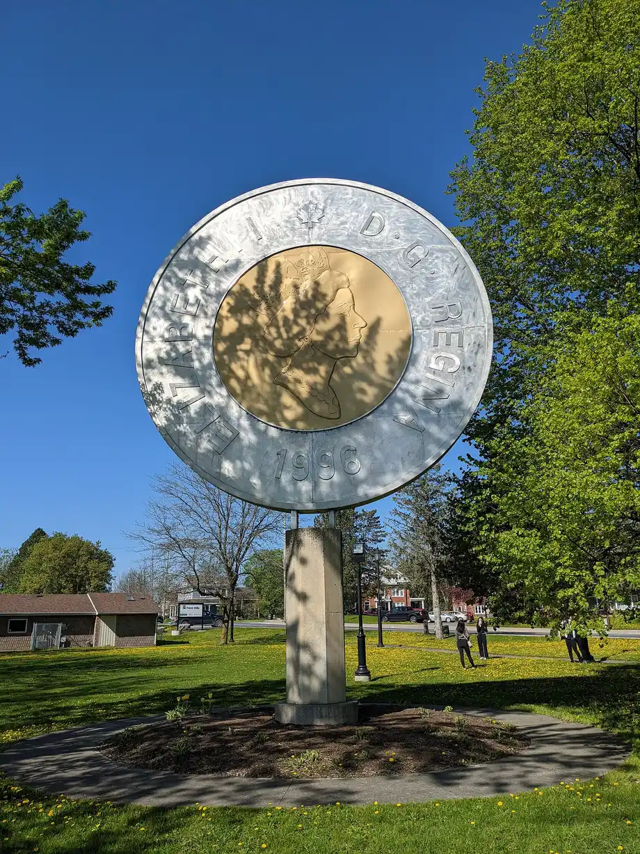 A giant sculpture of a Canadian two-dollar toonie coin standing in a park in Campbellford, Ontario
