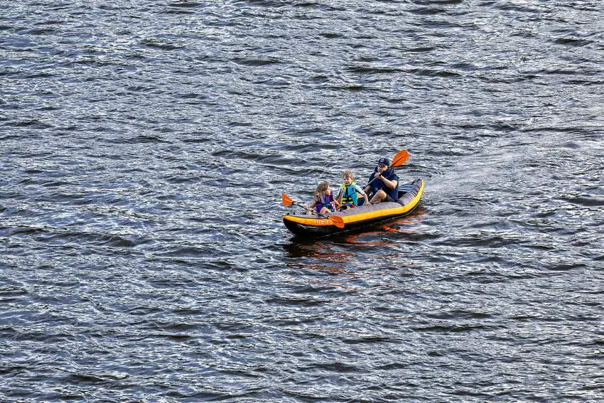 Two people paddling a canoe on the still water of Vermilion Lakes with a wooded ridge behind