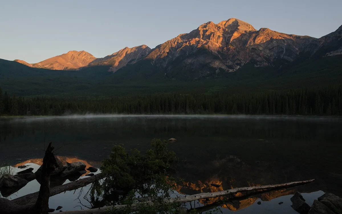 Pyramid Mountain mirrored in the calm surface of Pyramid Lake at dawn