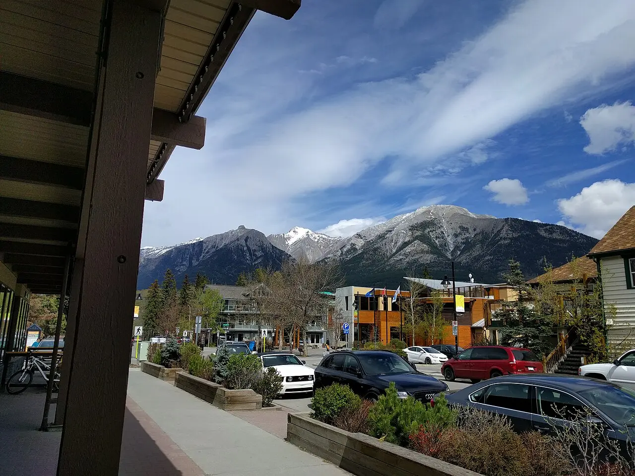 People walking a Canmore downtown sidewalk with shops and summer planters