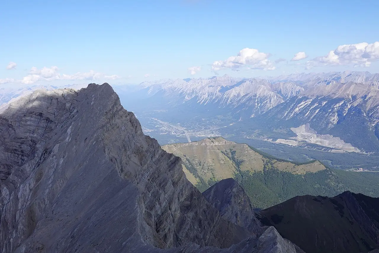 Canmore rooftops and spruce forest with limestone peaks stacked behind the town