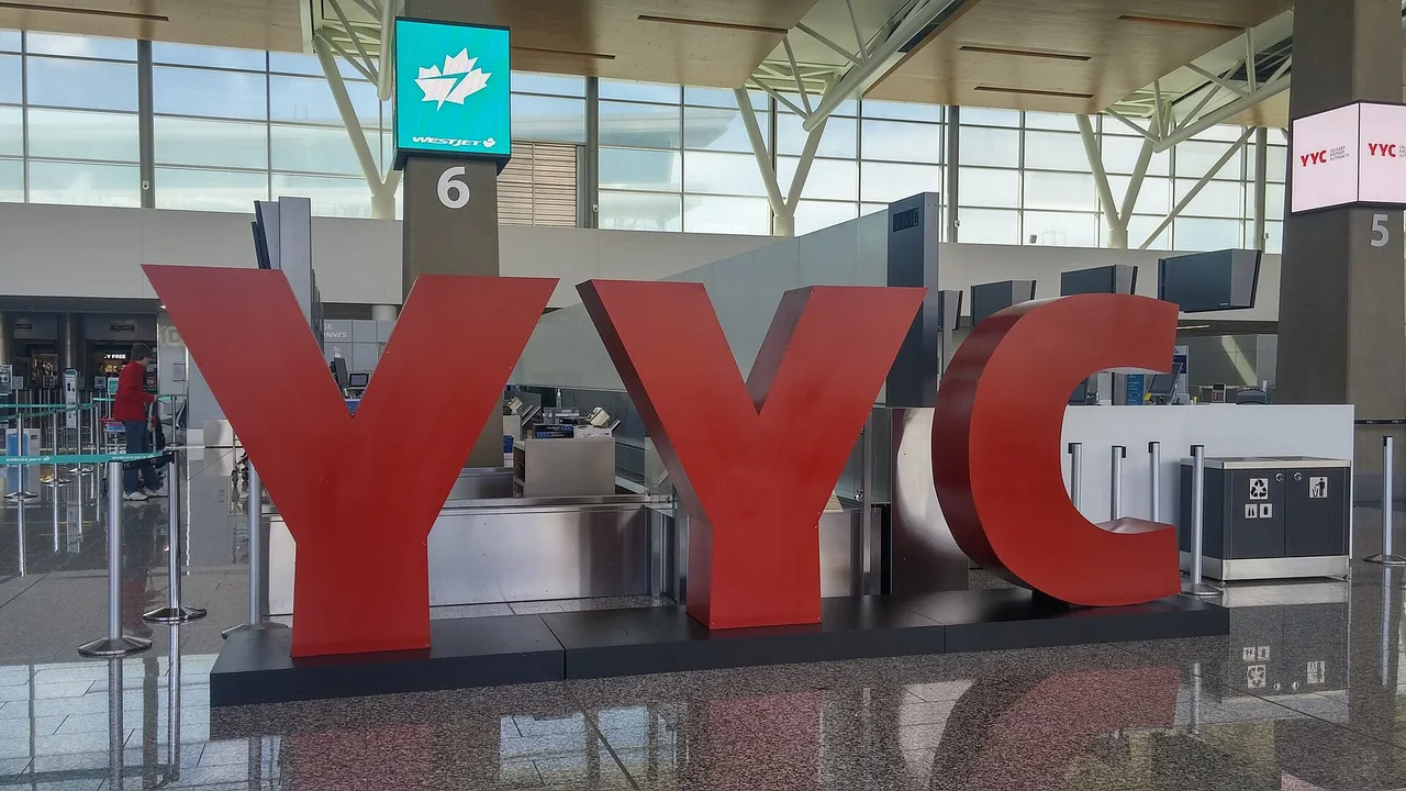Large red YYC letters in the departures hall at Calgary International Airport with WestJet check-in counters behind them
