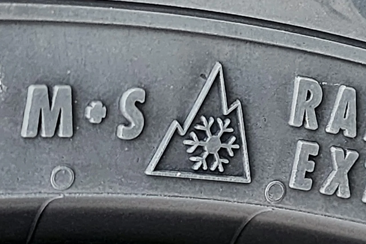 Close-up of a tire sidewall with the letters M+S embossed on the left and the mountain-and-snowflake symbol beside them