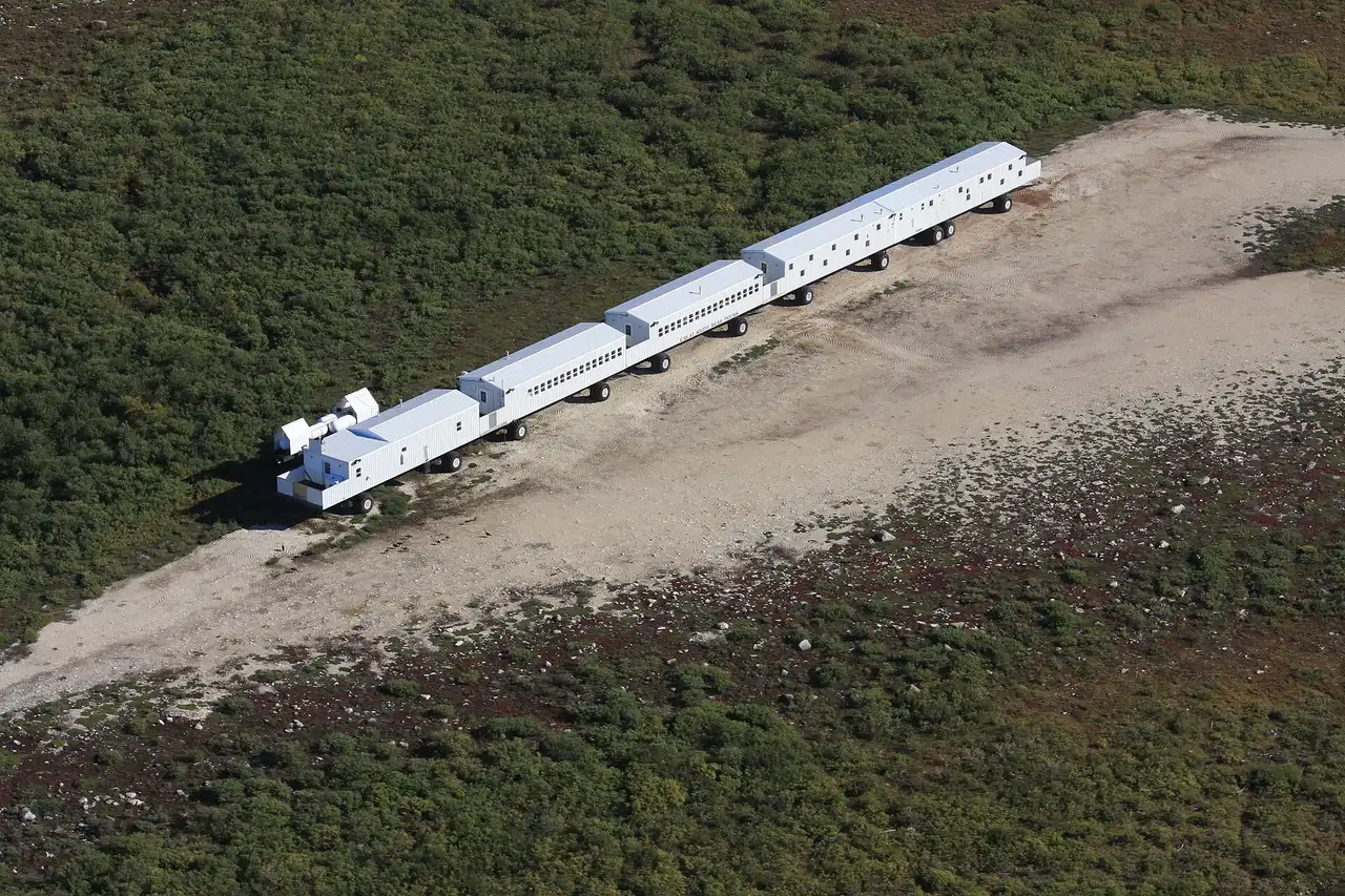An aerial view of the linked white units of the Tundra Buggy Lodge parked on the open tundra outside Churchill