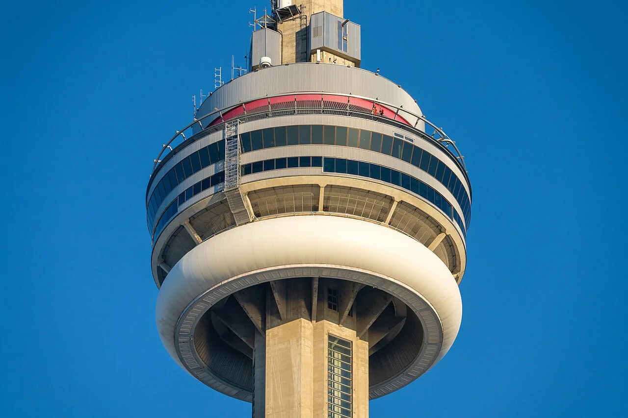 The main pod of the CN Tower with two harnessed EdgeWalk participants visible on the outer rim