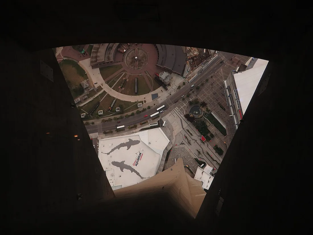 Visitors standing on the transparent glass floor of the CN Tower looking straight down at the streets below