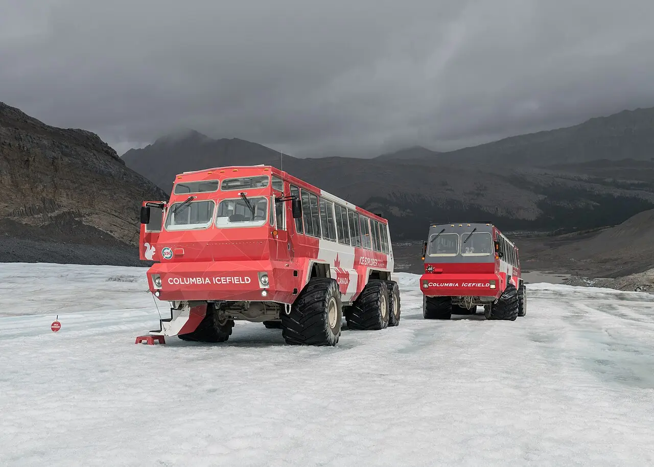 Two Ice Explorer vehicles parked on the Athabasca Glacier under cloudy skies