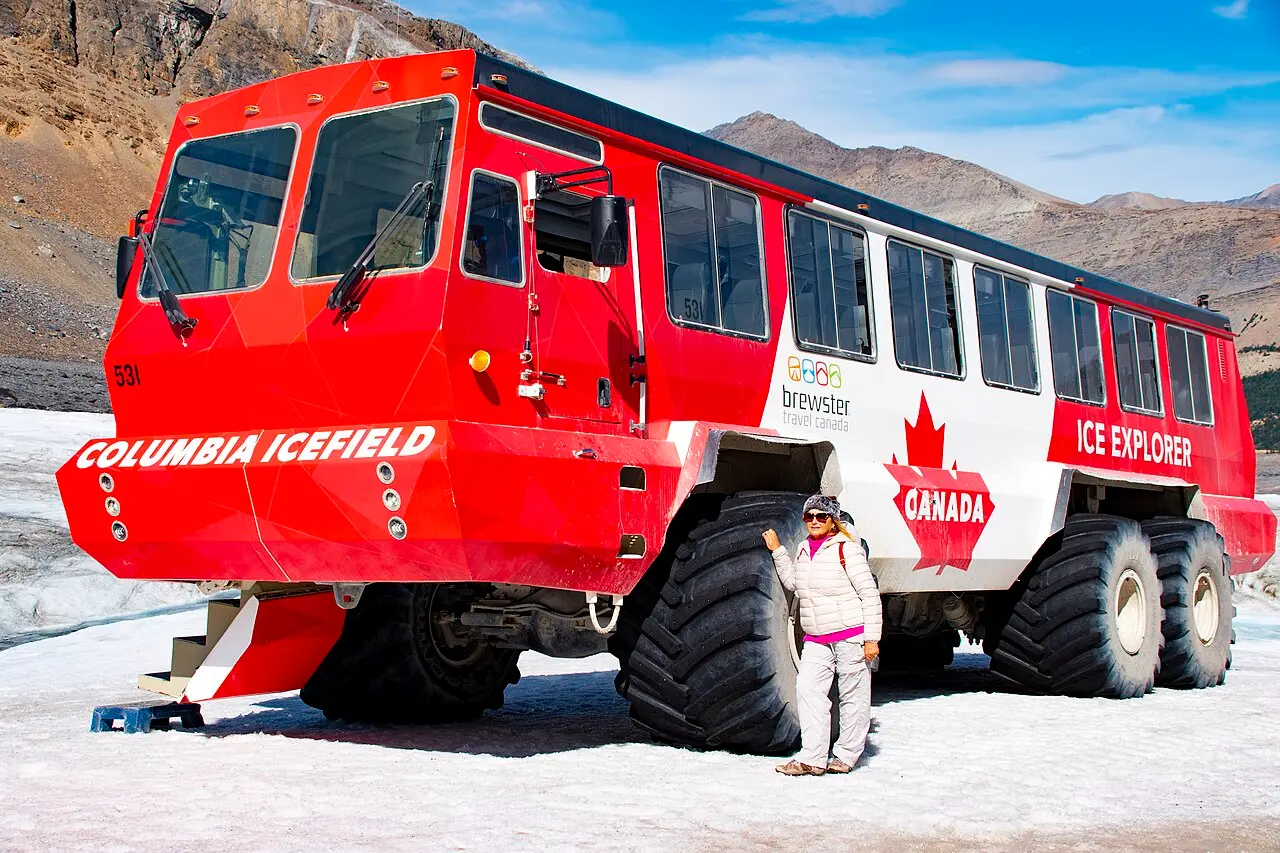An Ice Explorer vehicle on the Athabasca Glacier with visitors nearby