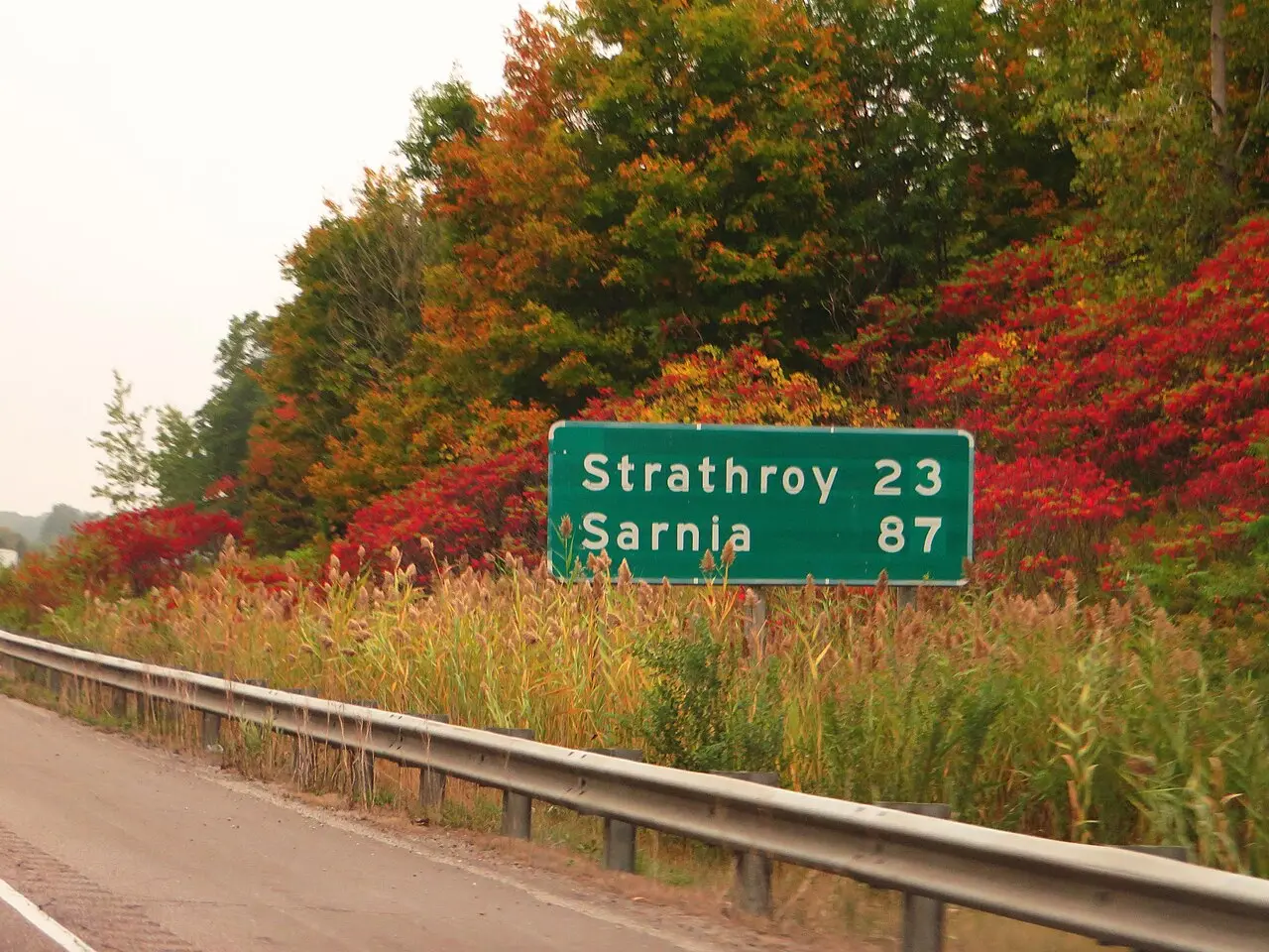 A green highway distance sign showing kilometres remaining to Strathroy on Highway 402 in Ontario
