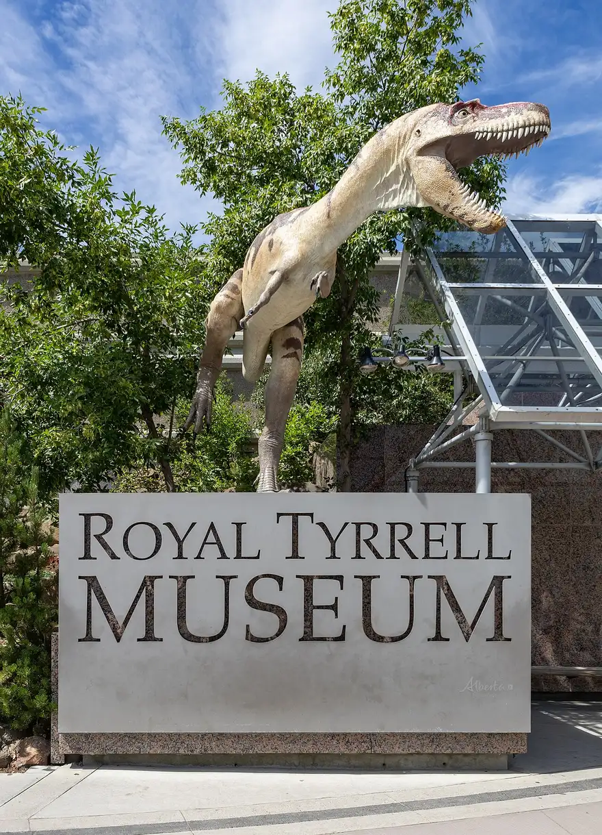 A life-size theropod dinosaur model above the Royal Tyrrell Museum sign at the entrance