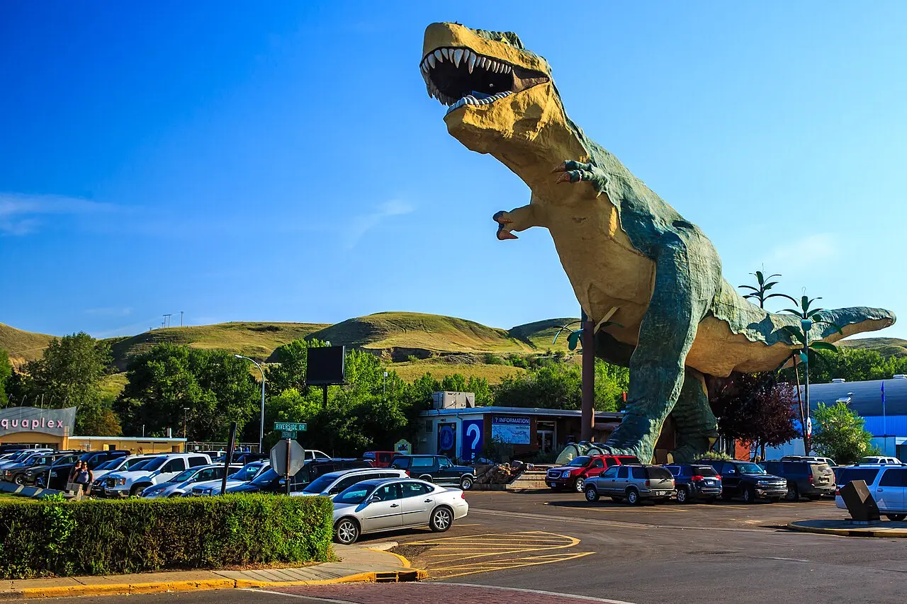 The World's Largest Dinosaur statue beside the visitor information centre and AquaPlex in downtown Drumheller, with badlands hills behind
