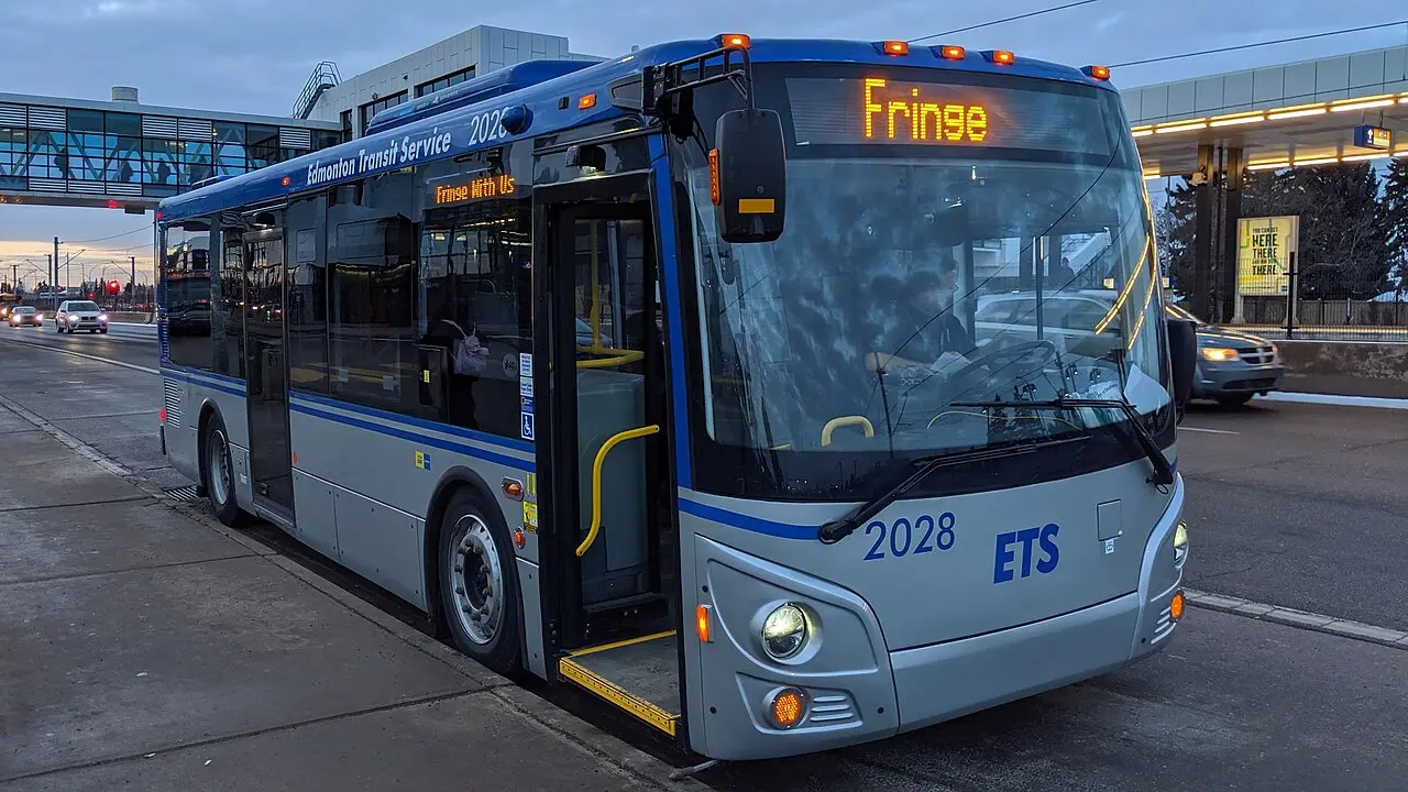 An Edmonton Transit Service bus wrapped in Fringe Festival branding on a city street