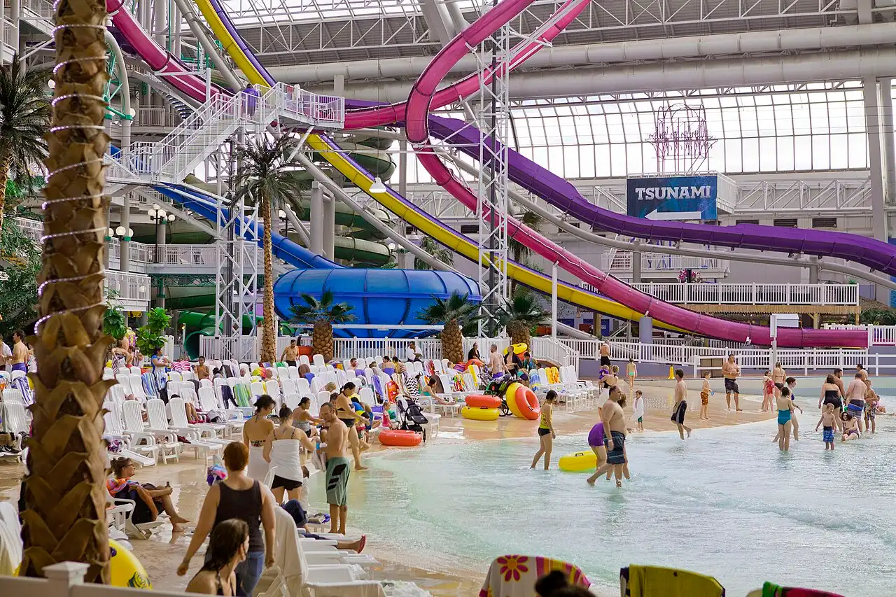 Swimmers in the wave pool at West Edmonton Mall World Waterpark under a glass roof with slides behind