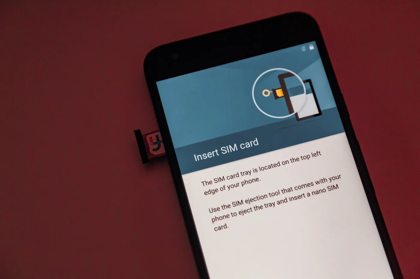 A hand inserting a nano SIM card into the tray of a modern smartphone