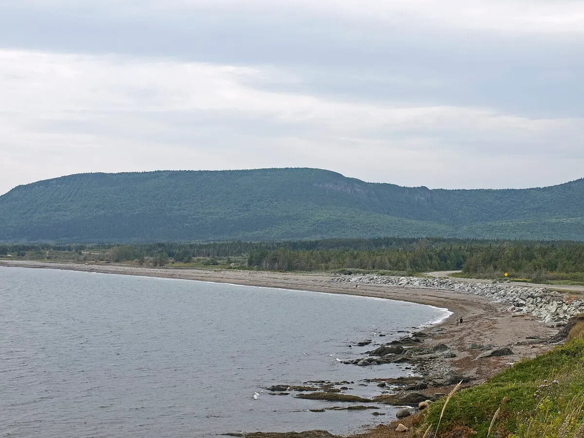 A crescent beach, coastal road and forested ridge in the north area of Forillon National Park
