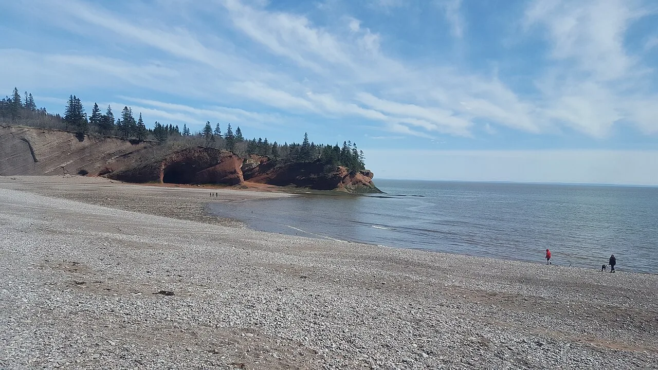 A red sandstone headland and pebble beach at low tide in Fundy National Park, New Brunswick