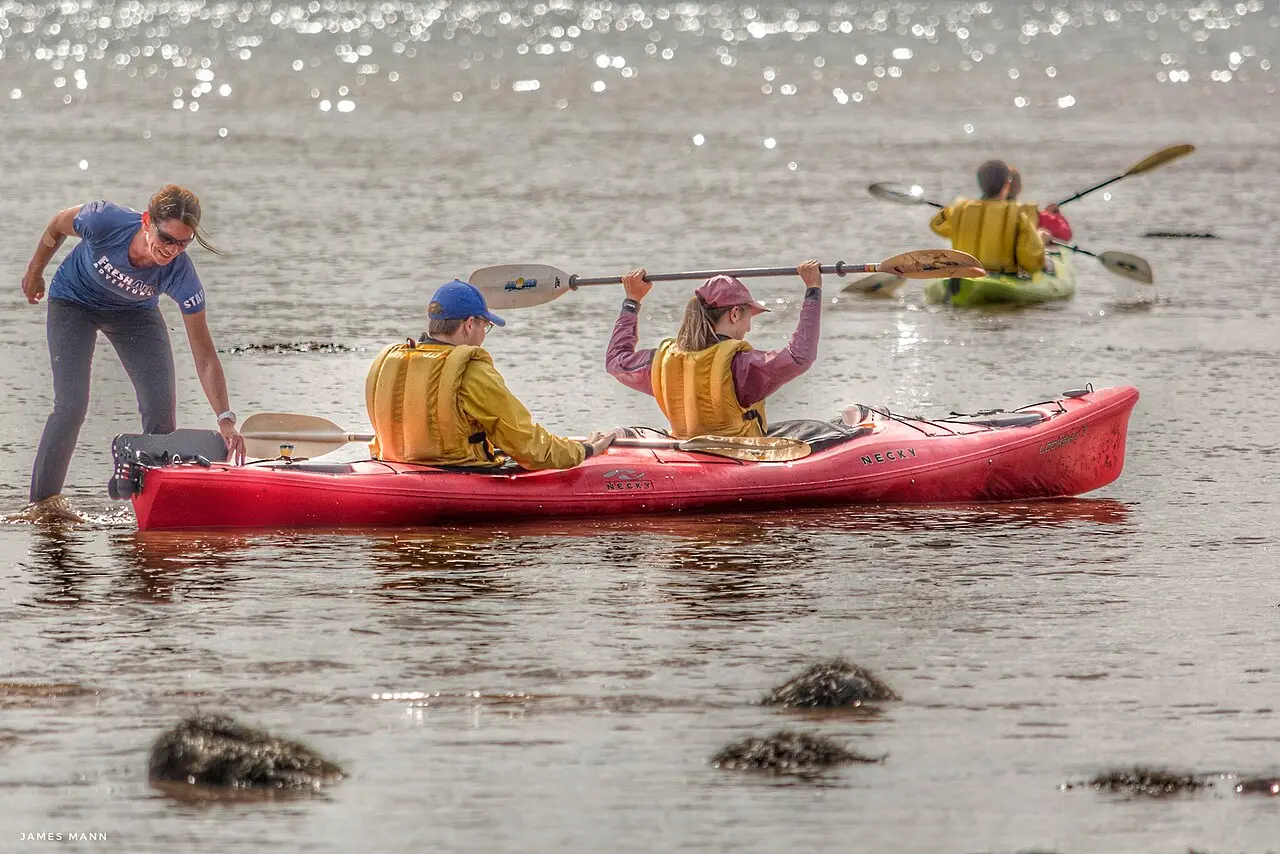 A guided sea kayak group launching from a muddy tidal flat near Fundy National Park