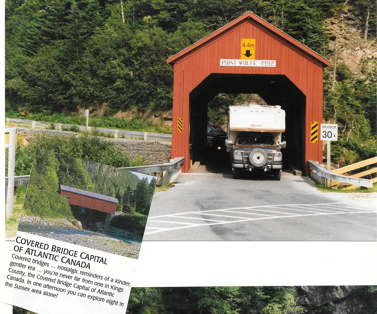 A pickup truck and camper trailer driving through the red Point Wolfe Covered Bridge in Fundy National Park