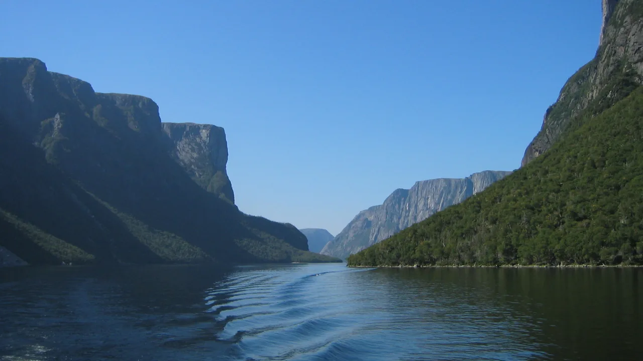 The cliff walls of the Western Brook Pond fjord seen from the tour boat, with its wake trailing across the water