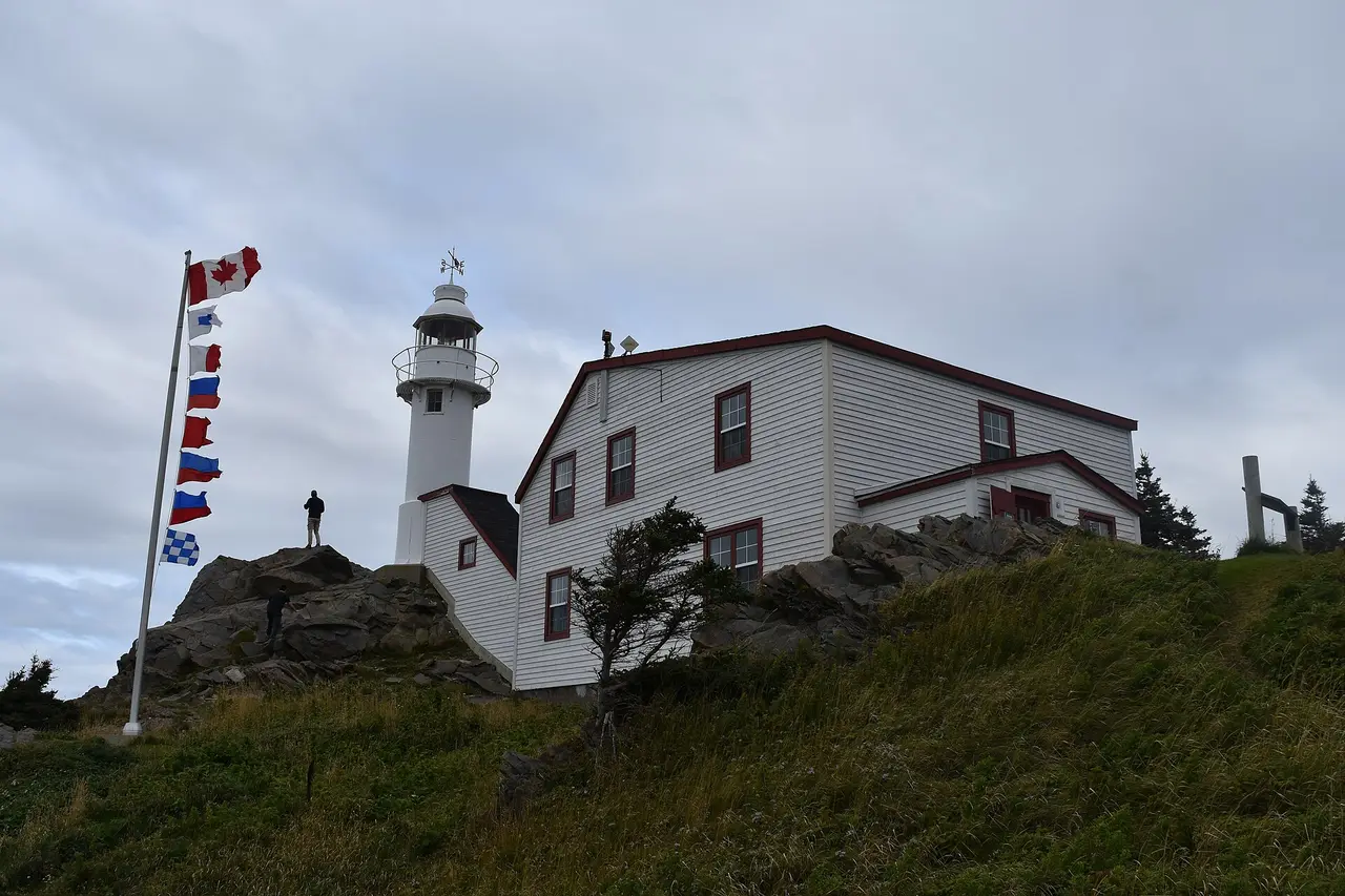The white Lobster Cove Head lighthouse on a rocky headland above the sea near Rocky Harbour