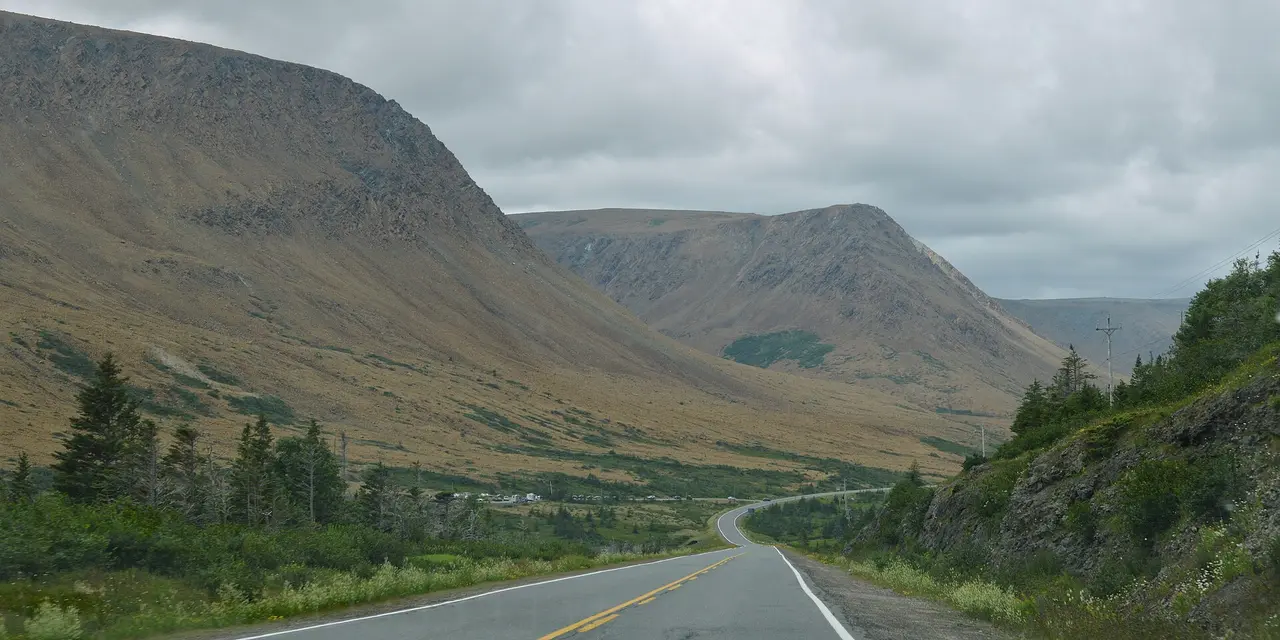 Route 431 running between the bare orange Tablelands and green forested hills in Gros Morne