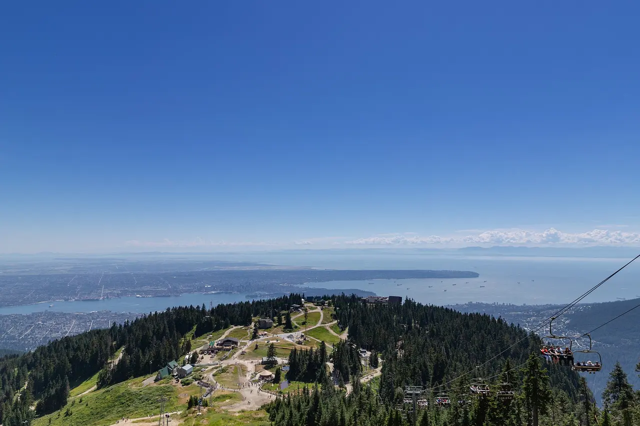 The Grouse Mountain summit buildings and chairlift with Vancouver and the water in the distance