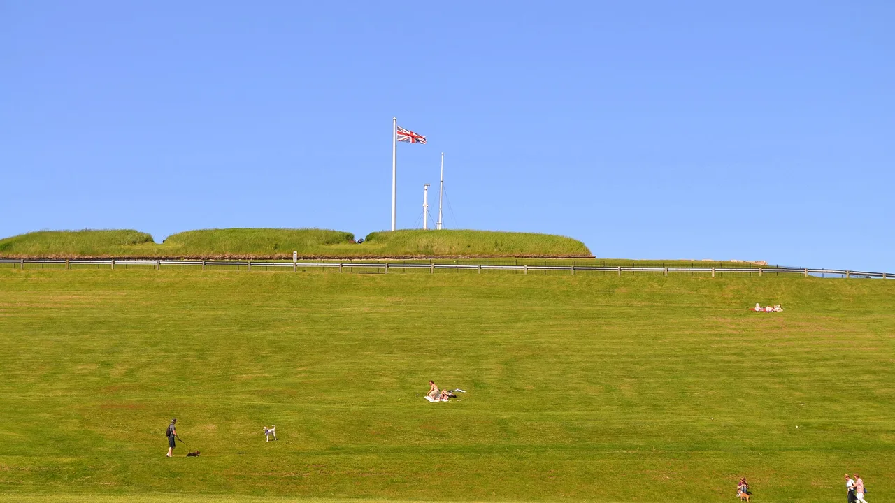 The grassy ramparts of Halifax Citadel with a Union Jack and signal masts on the hilltop under a blue sky
