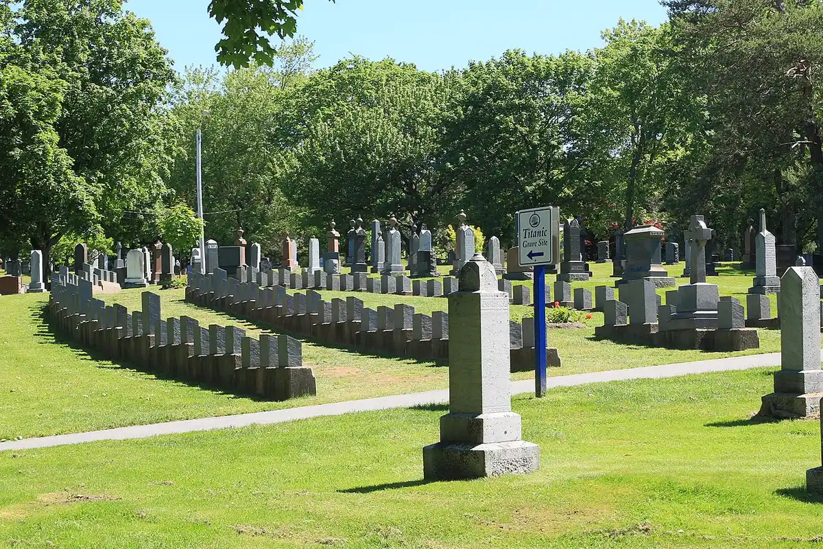 Rows of grey granite Titanic grave markers on green grass at Fairview Lawn Cemetery with a Titanic Grave Site sign