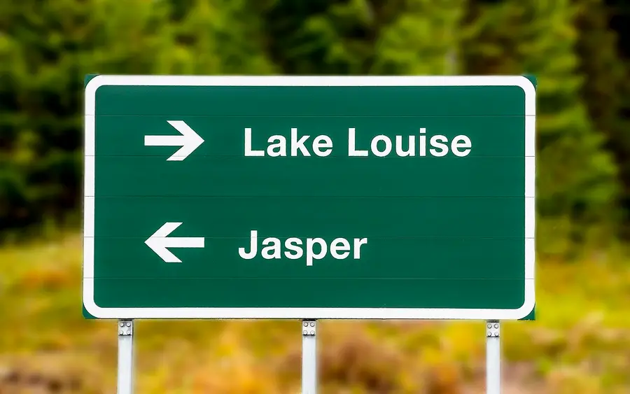 A green highway sign with arrows pointing right to Lake Louise and left to Jasper