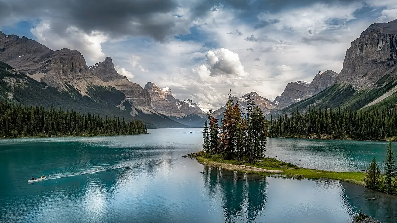 Spirit Island with its cluster of spruce trees on the turquoise water of Maligne Lake, ringed by snow-streaked peaks