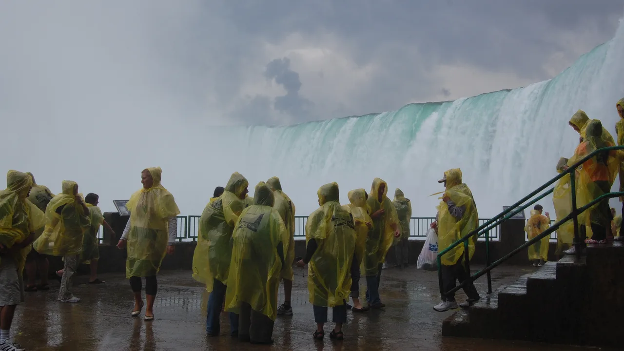 Visitors in yellow ponchos on the deck at the foot of the Horseshoe Falls, the curtain of water behind them