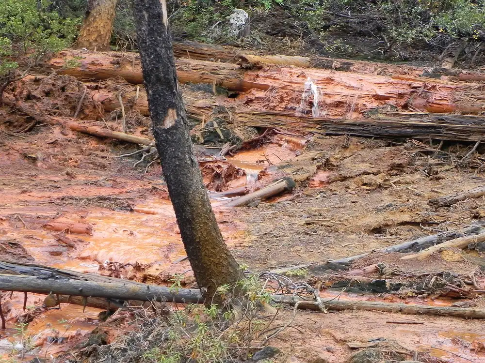 A stream running through bright orange ochre-stained ground at the Paint Pots