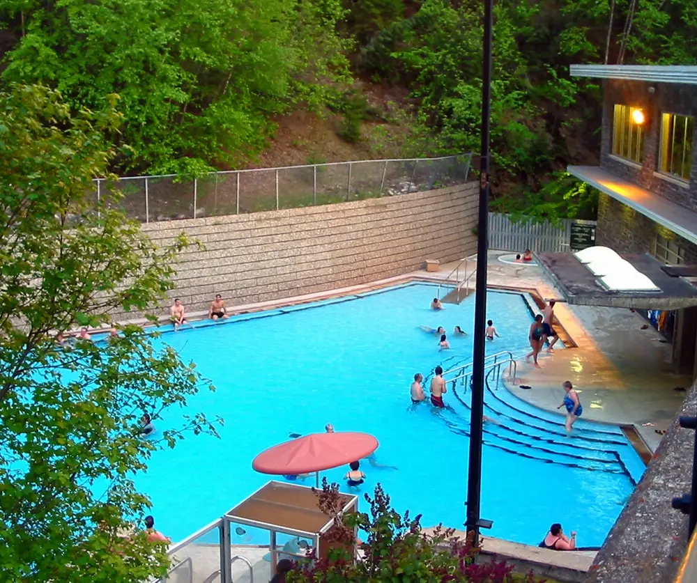 The outdoor hot pool at Radium Hot Springs surrounded by rock walls and mountain forest